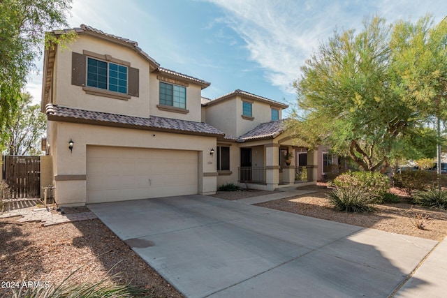 mediterranean / spanish house with an attached garage, a tiled roof, concrete driveway, and stucco siding