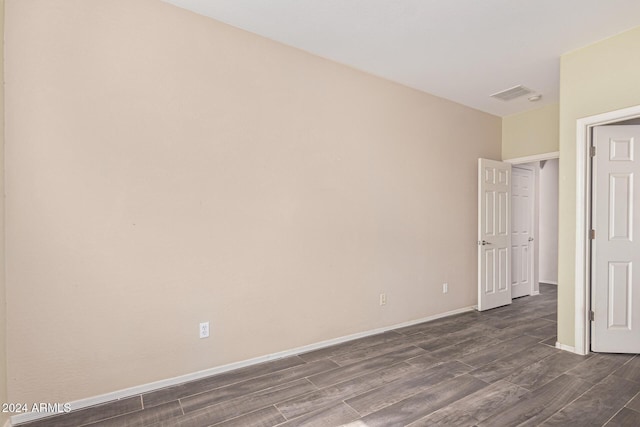 empty room featuring baseboards, visible vents, and dark wood finished floors