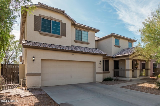 mediterranean / spanish home with an attached garage, fence, concrete driveway, a tiled roof, and stucco siding