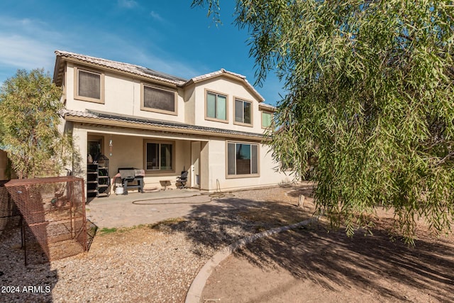 rear view of house with a patio, a tiled roof, and stucco siding