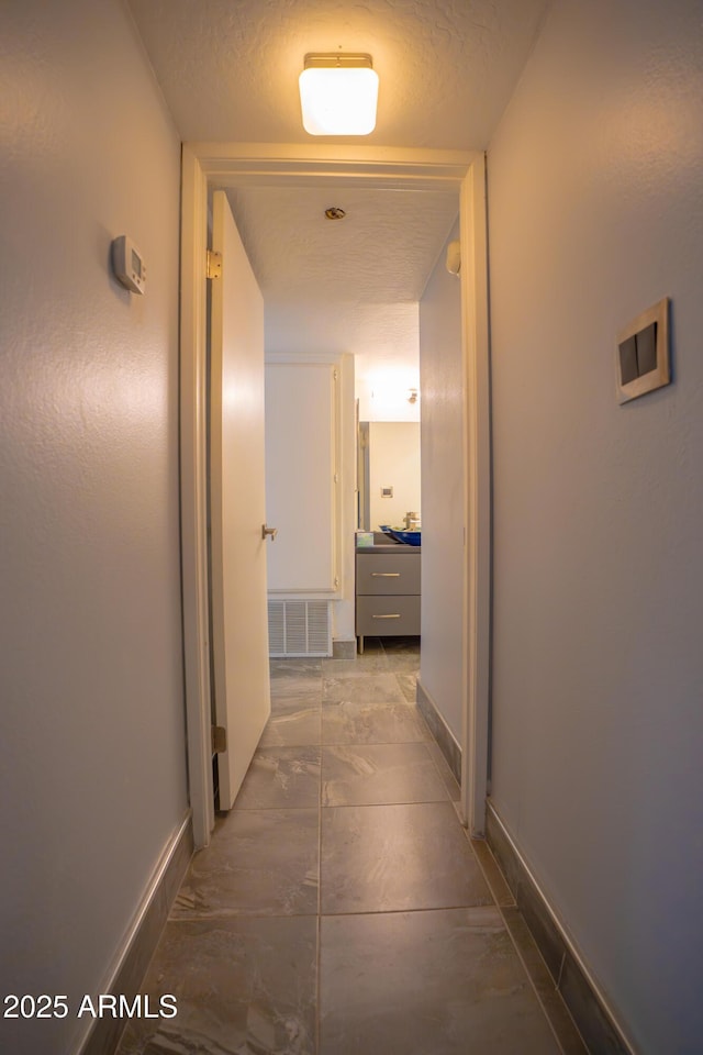 corridor with baseboards and dark marble finish floors