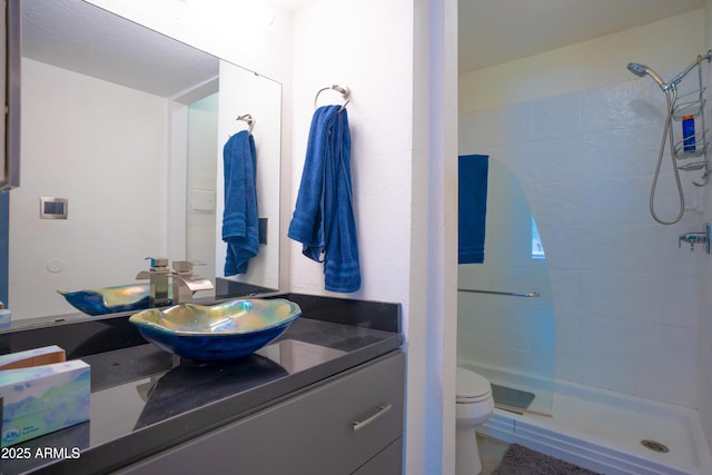 bathroom featuring tiled shower, vanity, and toilet