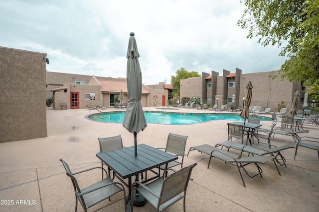 community pool with a patio area and fence