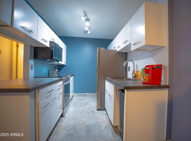 kitchen featuring appliances with stainless steel finishes, a sink, dark countertops, and white cabinets