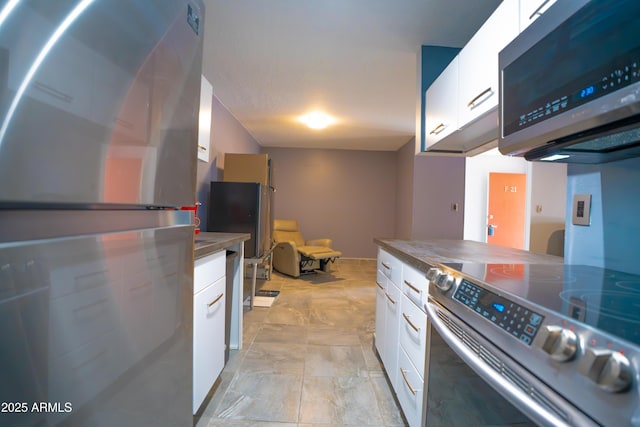 kitchen with appliances with stainless steel finishes, white cabinetry, and dark countertops