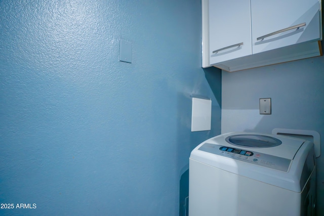 clothes washing area featuring cabinet space and washer / dryer