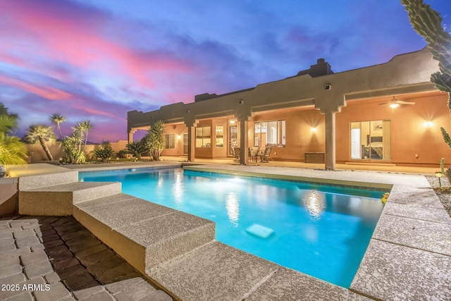 pool at dusk featuring a patio area and ceiling fan