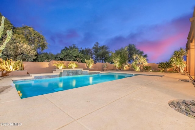 pool at dusk with pool water feature and a patio area