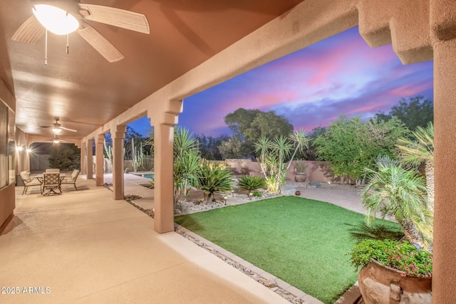 yard at dusk with a patio and ceiling fan