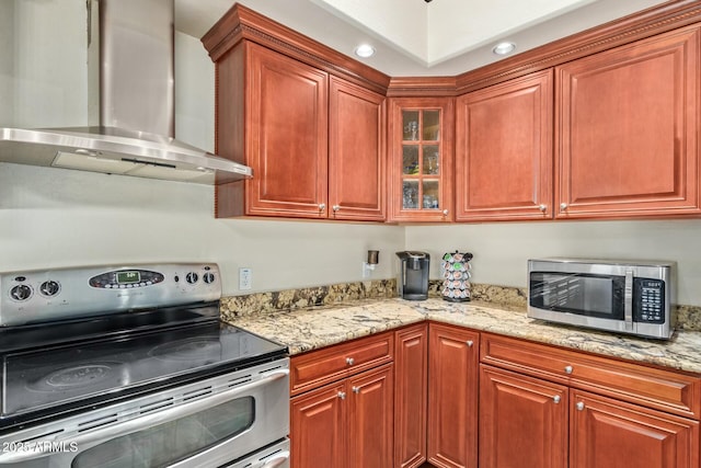 kitchen featuring light stone counters, stainless steel appliances, and wall chimney exhaust hood