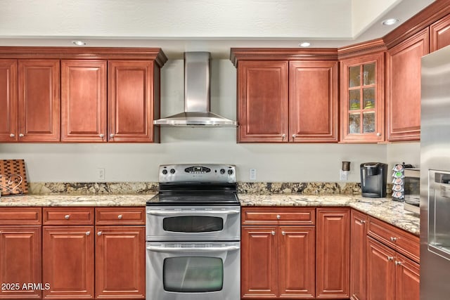 kitchen with light stone counters, wall chimney exhaust hood, and stainless steel appliances