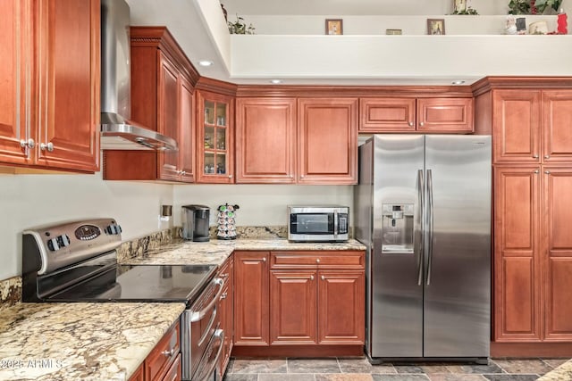 kitchen featuring light stone counters, stainless steel appliances, and wall chimney exhaust hood