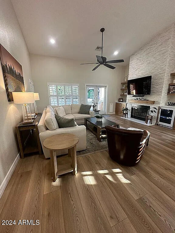 living room with hardwood / wood-style floors, ceiling fan, and a stone fireplace