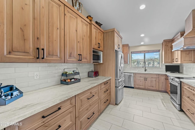 kitchen with light stone counters, a sink, custom exhaust hood, stainless steel appliances, and backsplash