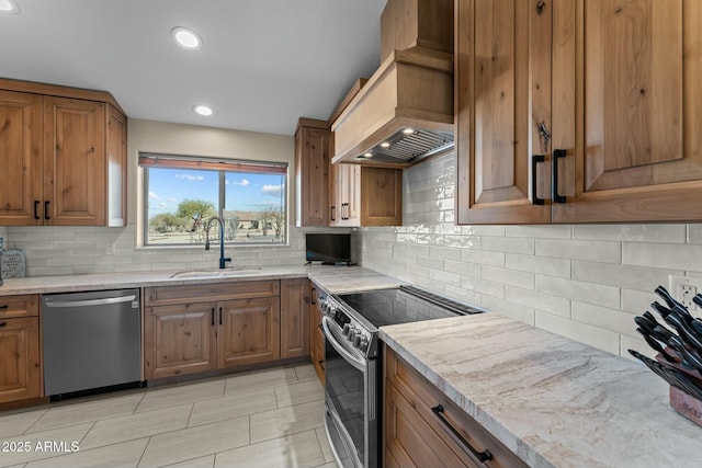 kitchen with brown cabinets, custom exhaust hood, stainless steel appliances, a sink, and light stone countertops