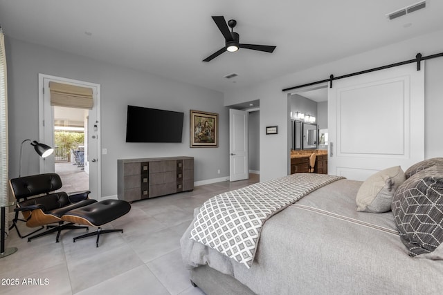 bedroom featuring light tile patterned floors, a barn door, visible vents, and baseboards