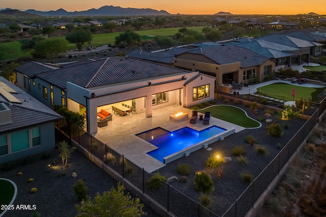 pool at dusk featuring an outdoor fire pit, a fenced backyard, a mountain view, area for grilling, and a patio area