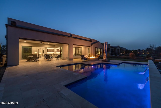 pool with a fire pit, outdoor dining area, and a patio