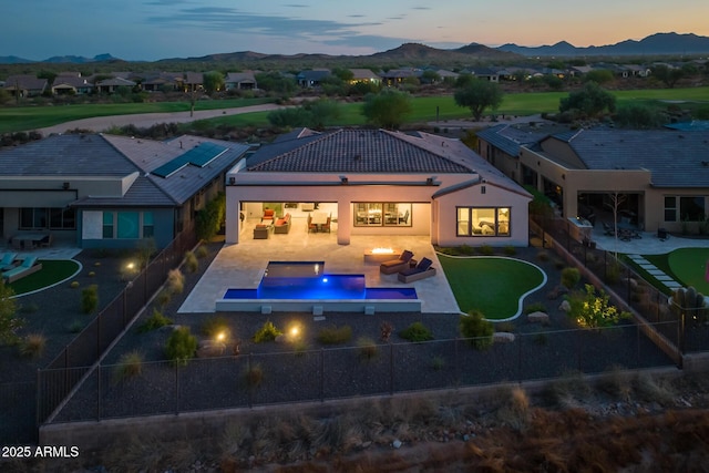 back of property at dusk featuring a fenced in pool, a patio, a fenced backyard, a tile roof, and a mountain view