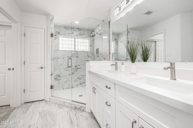 bathroom with marble finish floor, a marble finish shower, visible vents, and a sink