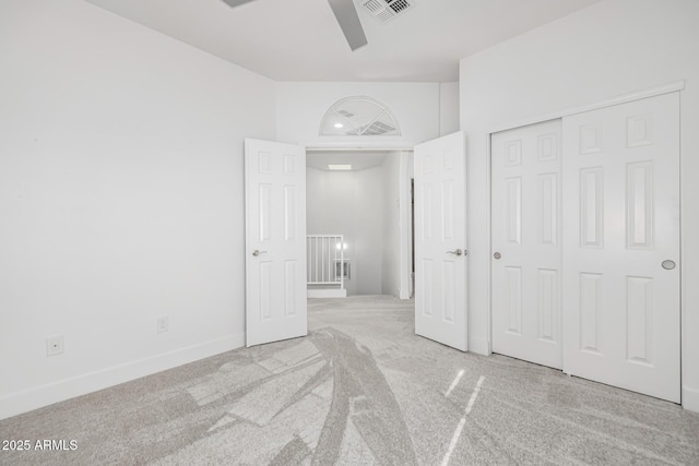 unfurnished bedroom with ceiling fan, a closet, a towering ceiling, and light colored carpet