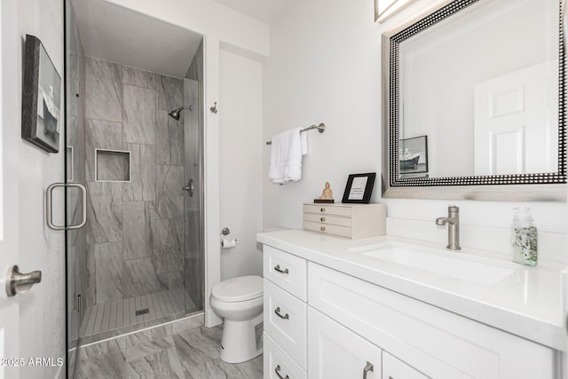 bathroom with marble finish floor, a shower stall, toilet, and vanity