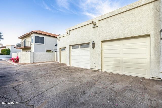 view of side of home with community garages, a tiled roof, and stucco siding