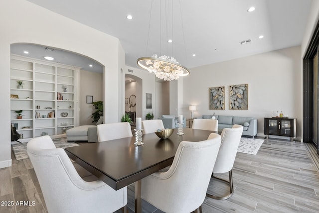 3045 W Feather Sound Dr, Phoenix, AZ 85086 - dining space featuring arched walkways, light wood finished floors, a chandelier, and recessed lighting