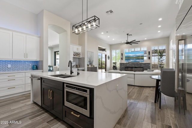 3045 W Feather Sound Dr, Phoenix, AZ 85086 - kitchen featuring a sink, stainless steel appliances, ceiling fan, white cabinets, and a stone fireplace