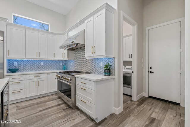 3045 W Feather Sound Dr, Phoenix, AZ 85086 - kitchen featuring stainless steel range, range hood, washer / dryer, white cabinets, and decorative backsplash