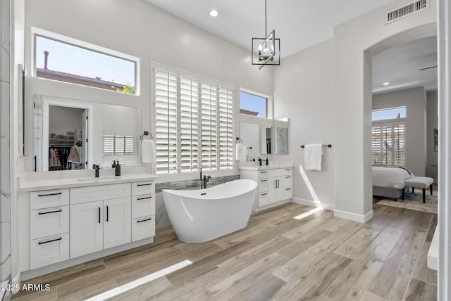 3045 W Feather Sound Dr, Phoenix, AZ 85086 - ensuite bathroom with two vanities, a soaking tub, wood finished floors, a walk in closet, and recessed lighting