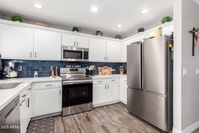 kitchen with light wood-type flooring, white cabinetry, backsplash, and appliances with stainless steel finishes