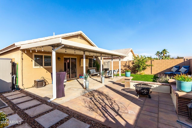 rear view of property featuring cooling unit, an outdoor fire pit, and a patio area