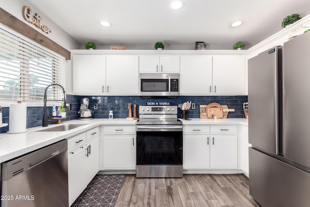 kitchen featuring tasteful backsplash, white cabinetry, sink, and stainless steel appliances