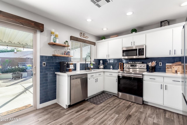 kitchen with wood-type flooring, stainless steel appliances, white cabinetry, and sink