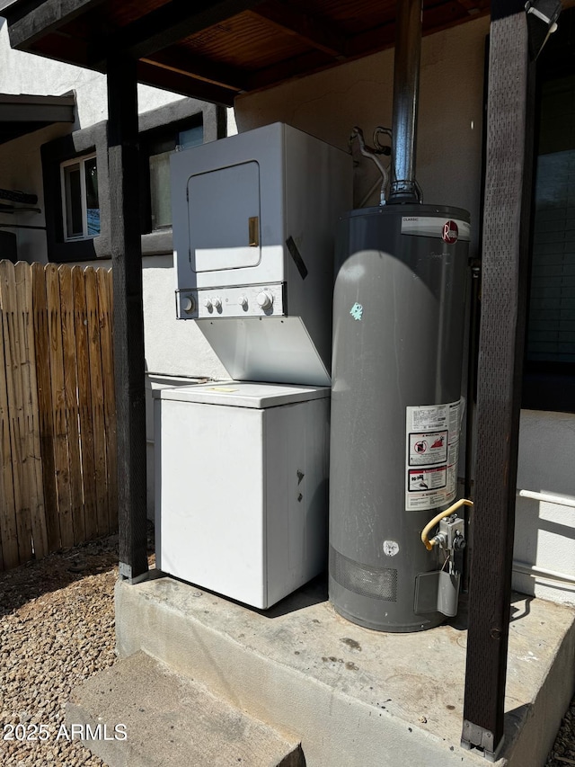 utility room with stacked washer / drying machine and gas water heater
