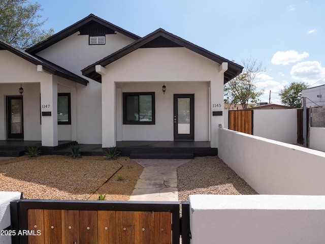 view of front of home featuring a porch, stucco siding, and a fenced front yard