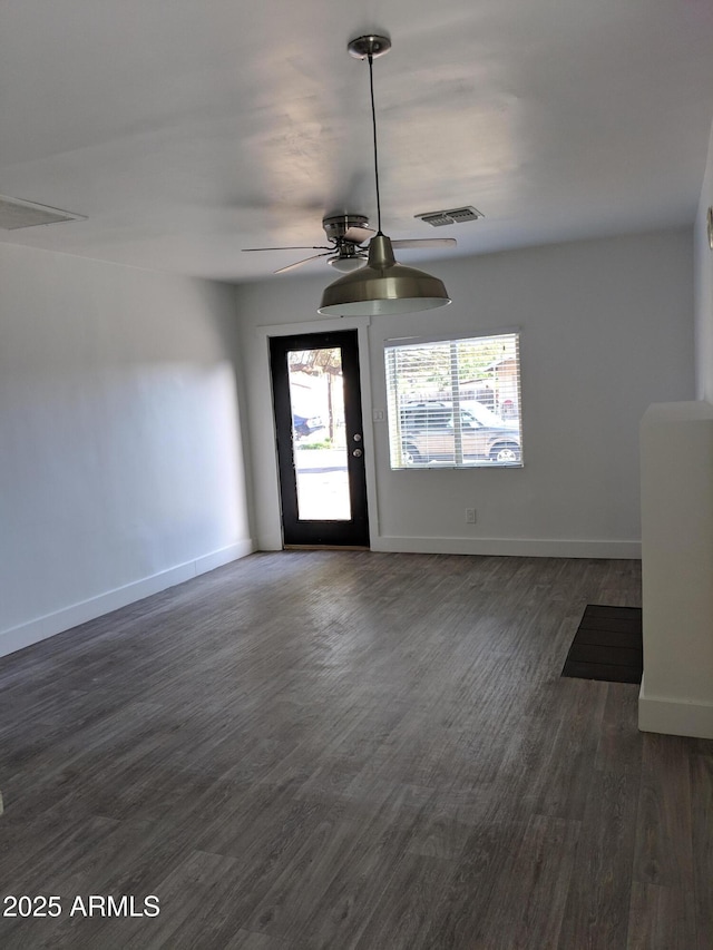 unfurnished living room featuring visible vents, baseboards, ceiling fan, and dark wood-style floors