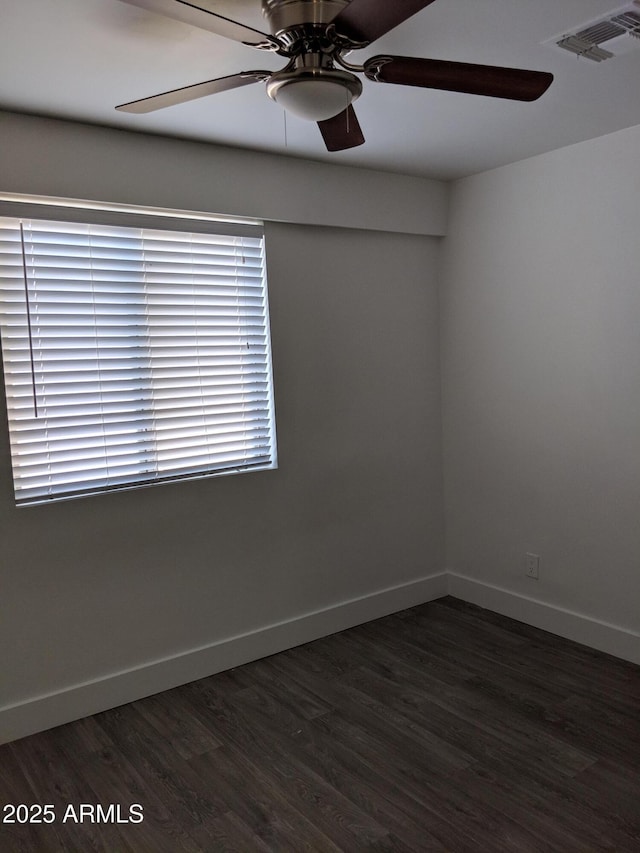 empty room with visible vents, dark wood-style flooring, baseboards, and ceiling fan