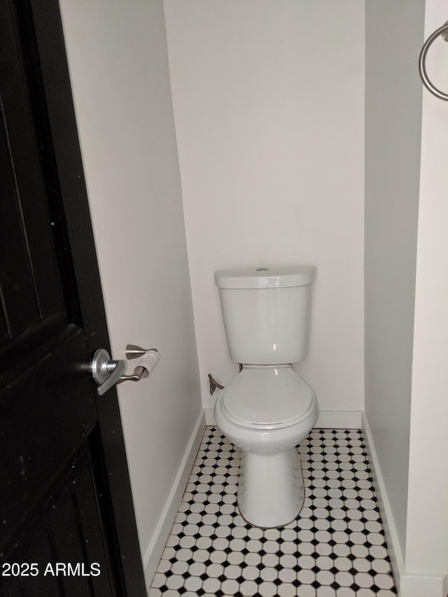 bathroom featuring baseboards, tile patterned flooring, and toilet