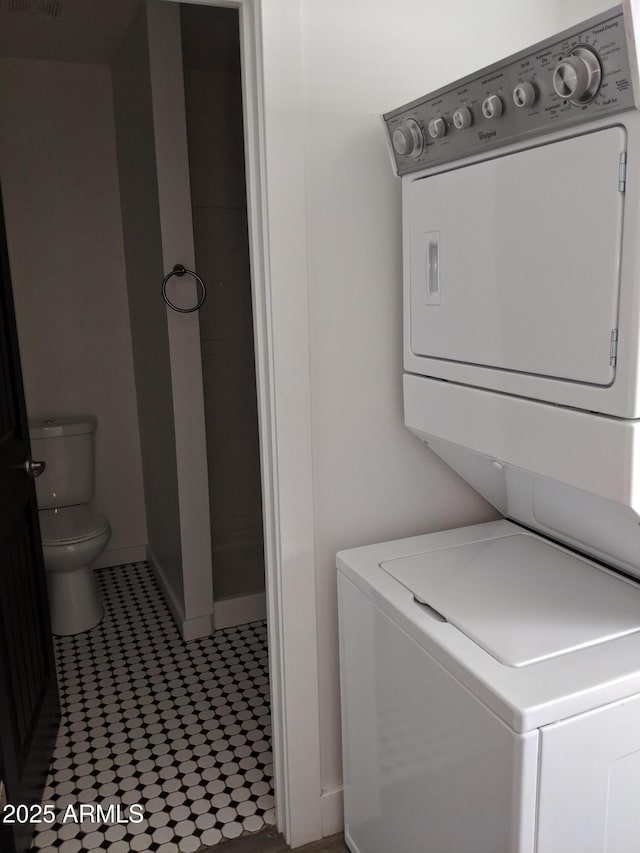 clothes washing area with laundry area, stacked washing maching and dryer, and baseboards