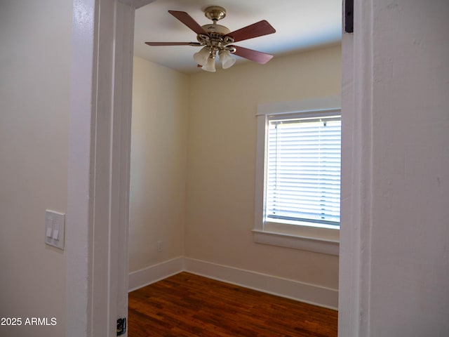 empty room featuring baseboards, dark wood finished floors, and ceiling fan