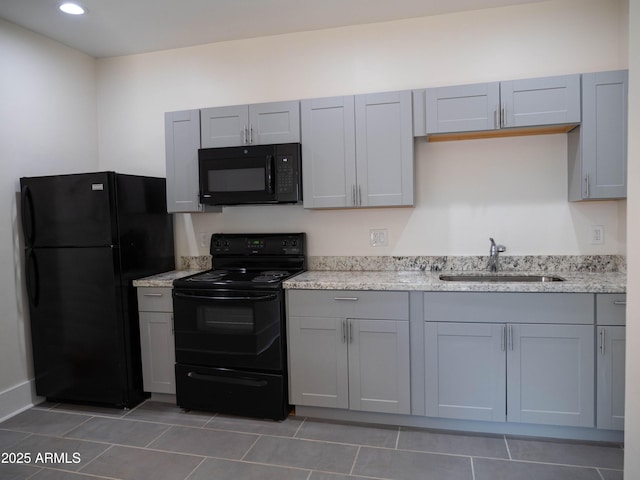 kitchen with gray cabinets, tile patterned flooring, black appliances, and a sink
