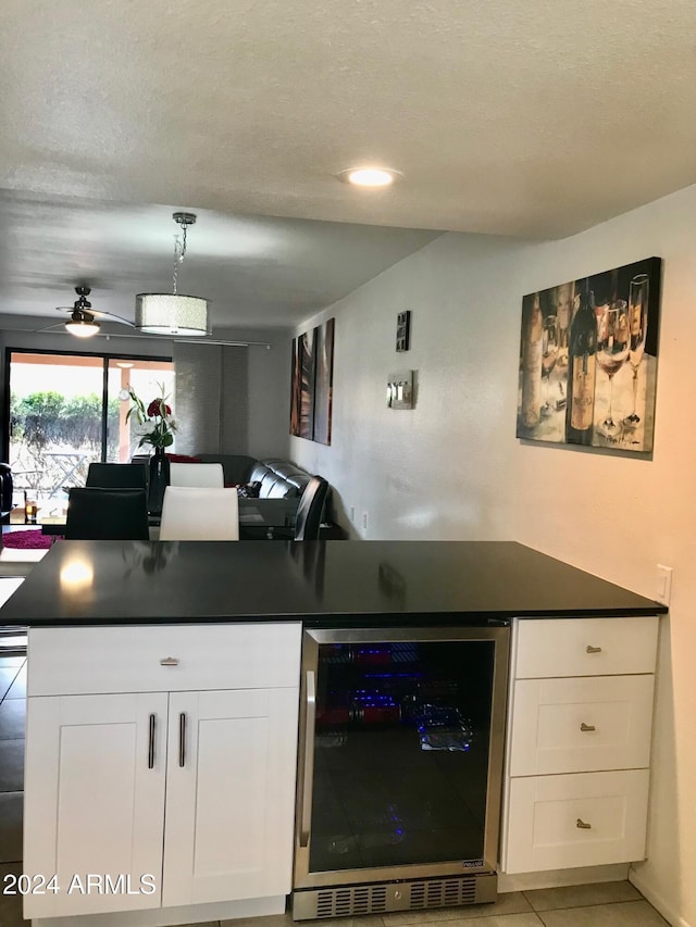 kitchen featuring white cabinetry, wine cooler, hanging light fixtures, light tile patterned floors, and ceiling fan