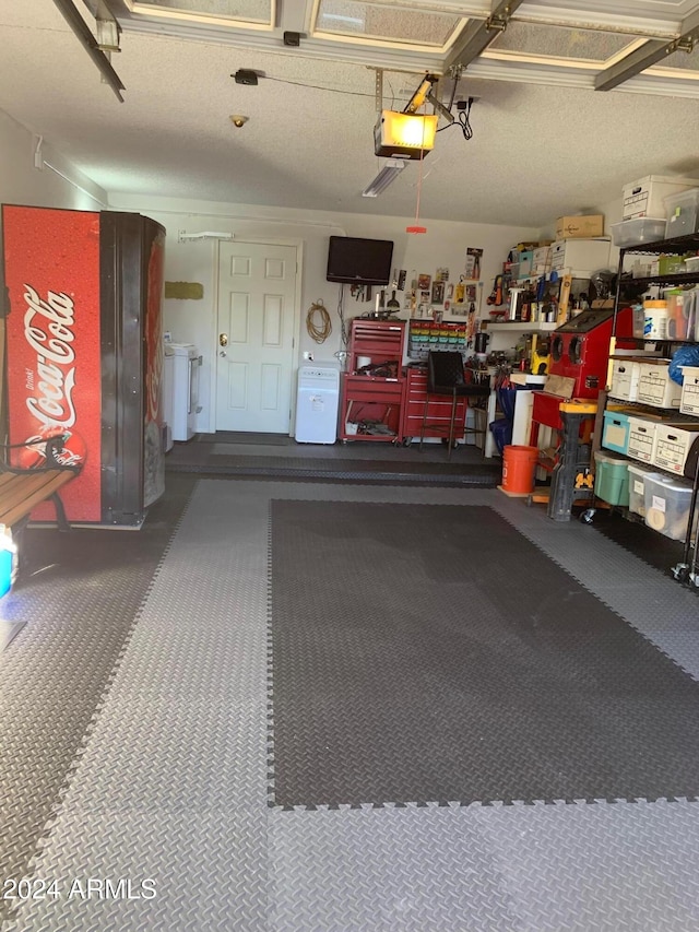 garage featuring a garage door opener, washer / dryer, and a workshop area