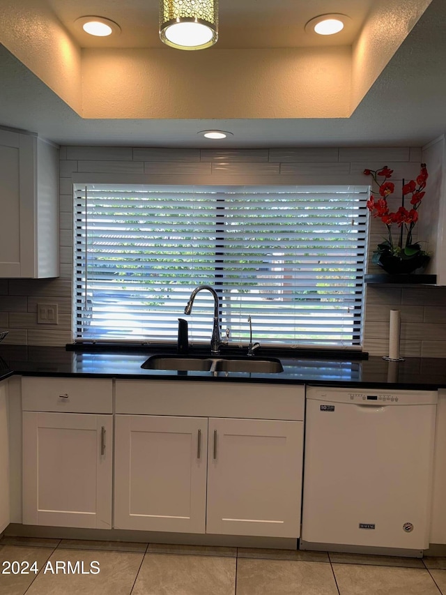 kitchen featuring sink, light tile patterned floors, dishwasher, white cabinetry, and tasteful backsplash