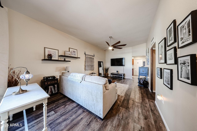 living area with dark wood finished floors, a ceiling fan, and baseboards