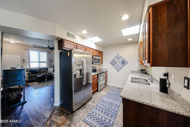 kitchen featuring a textured ceiling, stainless steel appliances, a sink, visible vents, and a ceiling fan