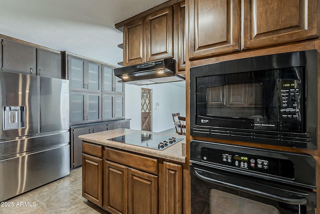 2432 W Echo Ln, Phoenix, AZ 85021 - kitchen with black appliances, under cabinet range hood, light countertops, light tile patterned floors, and glass insert cabinets