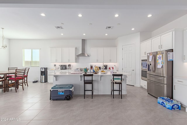 kitchen with wall chimney exhaust hood, a breakfast bar area, appliances with stainless steel finishes, and a kitchen island with sink